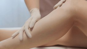 Close up video of female legs after removing hair procedure in spa salon by a cosmetologist in gloves, body care concept. Post-epil emulsion cream oil product.