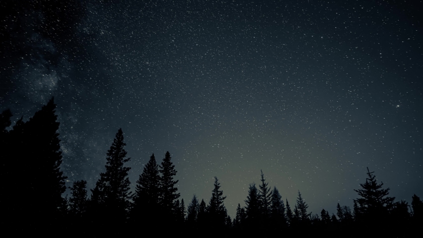 Time lapse of stars, including the Milky Way, move above a silhouette forest. Also satellites and meteors streak across sky.
 Royalty-Free Stock Footage #1093976309