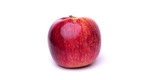 4K Video of a single apple slowly turned on a white background.