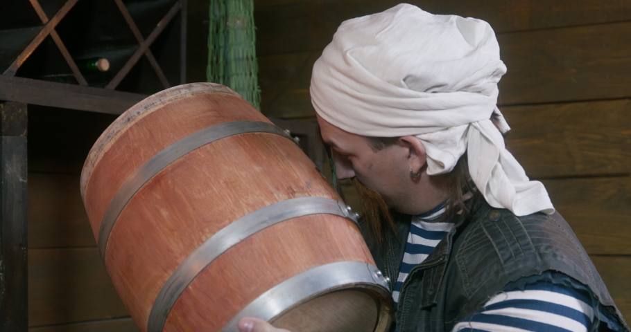 Oenophile kisses oak barrel with aged wine, rejoices in stock. Man warehouse worker in traditional winery in basement arranges drinks. Authentic traditional wine production. Sailor supplies alcohol  | Shutterstock HD Video #1093980219