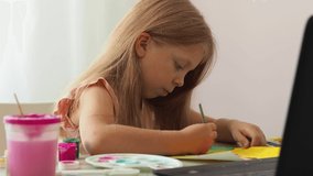 The girl draws a picture with paints.Children's bright drawing with watercolors and gouache paints.School of preschool online drawing. Distance Art School. Children's creativity.