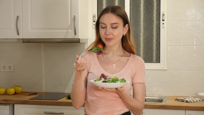 Portrait of positive vegeterian woman eating fresh vegetable salad at home. 