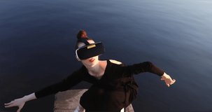 Young woman uses virtual or augmented reality glasses in magic atmosphere of dawn rays, female VR headset user. Digital interactive art performance, entertainment of future. Dance.