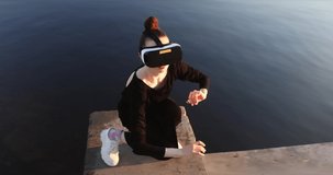 Young woman uses virtual or augmented reality glasses in magic atmosphere of dawn rays, female VR headset user. Digital interactive art performance, entertainment of future. Dance.