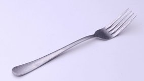 Fork is spinning on the table, cutlery video on a white background.