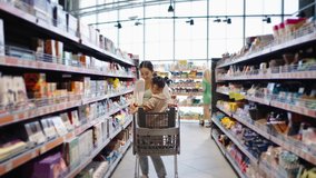 Young mother looks for products with excited daughter walking among racks. Preschooler girl enjoys riding in cart and going shopping with businesswoman - Powered by Shutterstock - Get 15% off with code: PIKWIZARD15