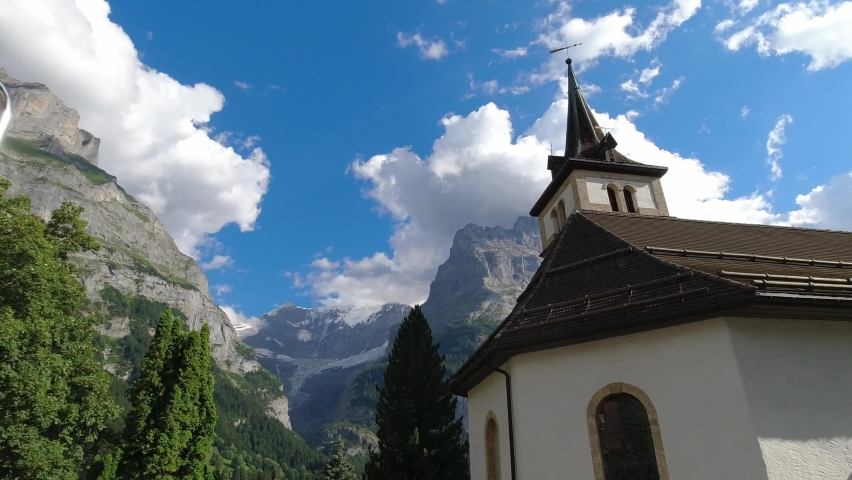 Catholic church in alpine valley. Religious building surrounded by tall mountains in Switzerland