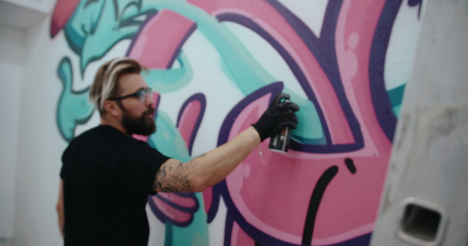 Graffiti artist painting on gallery wall. handheld camera