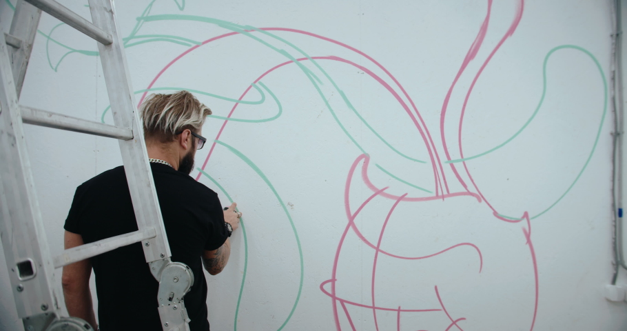 Graffiti artist painting on gallery wall. handheld camera