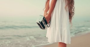 Beauty young lady making video film with old vintage camera of beautiful dancing sea waves during colorful sunrise on the beach