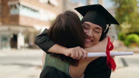 Two women mother and graduated daughter holding diploma kissing at street Arkistovideo