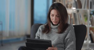 Young caucasian woman business lady sitting in chair using smartphone online digital application technology gadget staying home in living room.