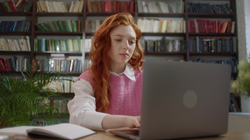 Girl with red hair college student using laptop computer watching distance online learning seminar class, remote university webinar or having virtual classroom meeting in university creative space. Royalty-Free Stock Footage #1093993719