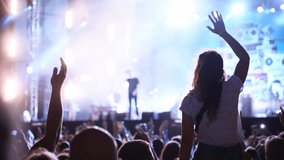Woman sits on boyfriend shoulders waving hands at music concert on open air fest. Crowd applause, jump, wave hands and dance at favourite band performance on stage. Bright illumination. - Powered by Shutterstock - Get 15% off with code: PIKWIZARD15