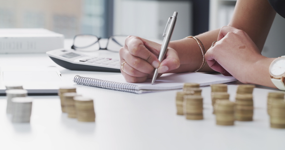 Bank, coins and hands writing in tax files for financial budget or consulting on desk at work. Economy, money and accountant working on corporate finance documents and administration for management | Shutterstock HD Video #1093998727