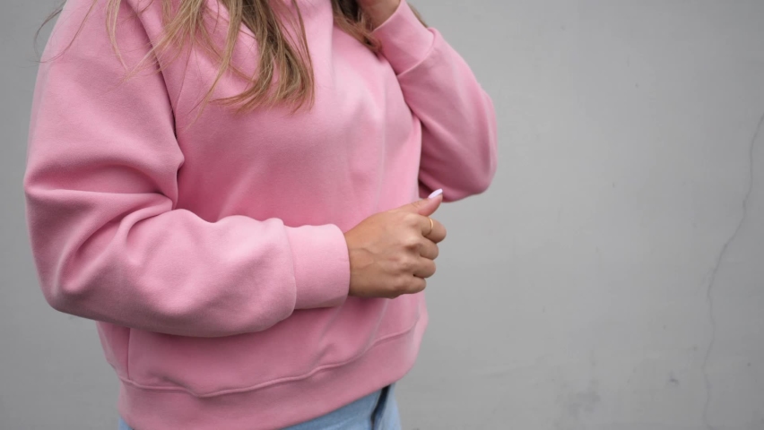 A girl in a pink sweater ends a phone conversation on a smartphone by tapping on the screen. People and technology.
