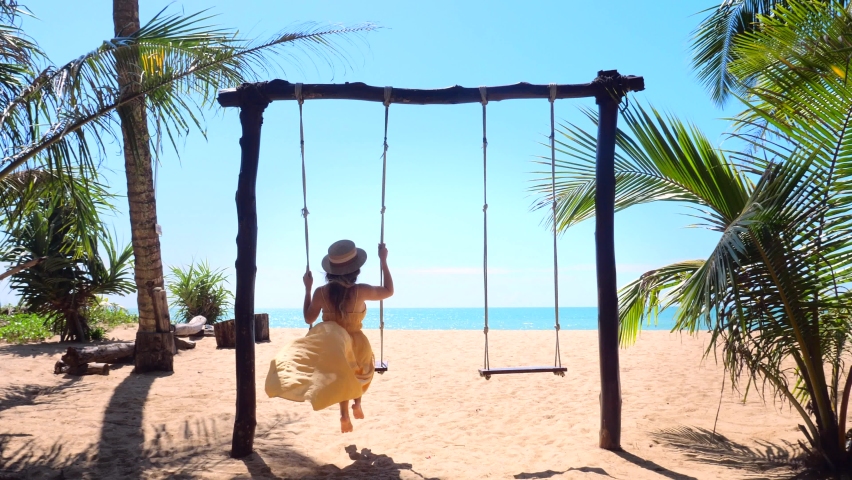 Vacation cheerful woman in dress and straw hat, swinging for joy, relax and leisure. Travel girl enjoys her holidays at luxury resort near sea.  | Shutterstock HD Video #1094007633
