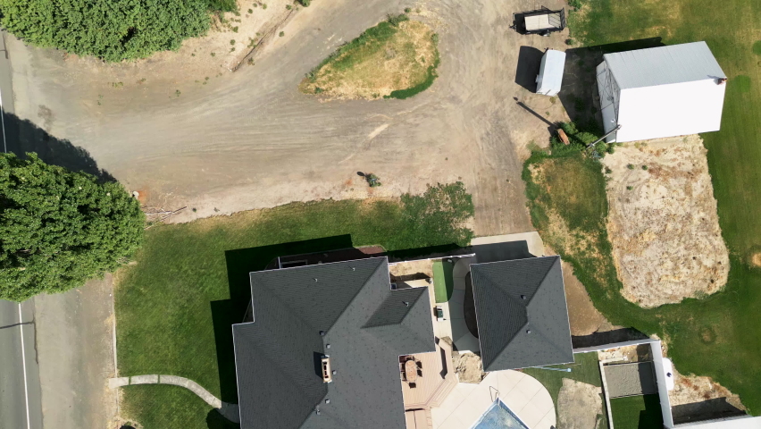 Aerial-Top down-Over farm buildings, vehicles and trees - tilt to golden grain fields stretching off to the horizon