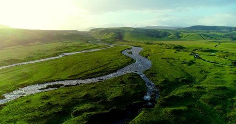 Wonderful natural scenery captured in Iceland taken during magic hour showing sunset over green grassy plain. The sun shining gently over making the grass shine and a beautiful small river with its wa Stock Video