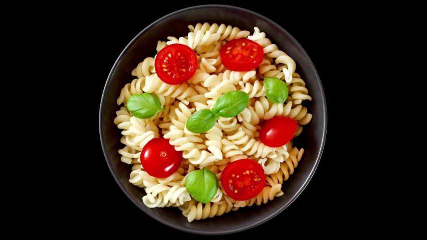 Fusilli pasta cooked with tomatoes and basil in dark gray bowl, top view, rotating isolated on black background, turning, close-up macro.
 | Shutterstock HD Video #1094026075
