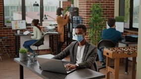 Company employee with face mask using laptop to create analysis, working with online research information and data charts to plan project report. Business man at office job during pandemic. - Powered by Shutterstock - Get 15% off with code: PIKWIZARD15