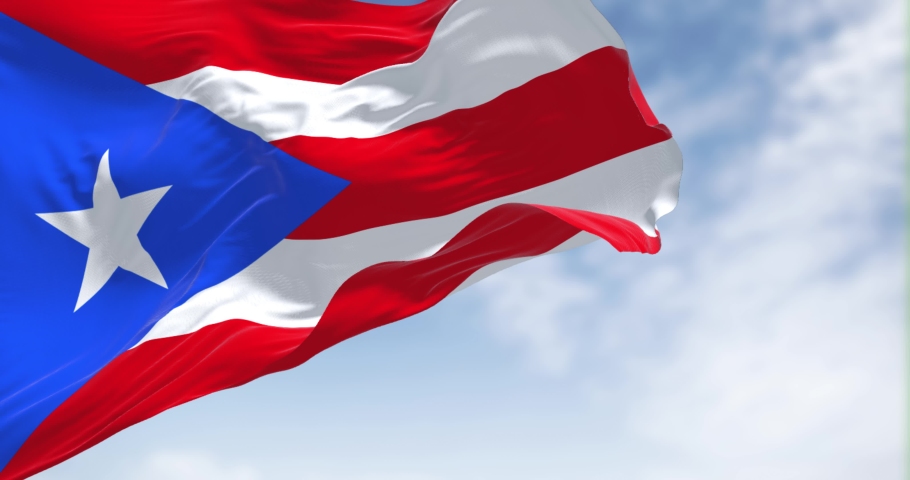 Flag of Puerto Rico waving in the wind on a clear day. Puerto Rico is a Caribbean island and unincorporated territory of the United States. Seamless loop in slow motion