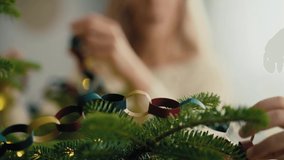 Close up of caucasian little girl and mother decorating Christmas tree with DIY paper chain. Shot with RED helium camera in 8K.  