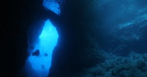  scuba diver exploring around a reef  and caves underwater deep blue water big rocks and bubbles ocean scenery nice blue light 
