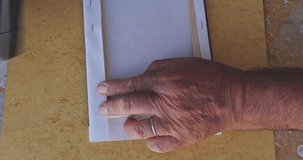 Close up shot of a mans hands stretching and stapling a canvas print on to the stretcher bars. vertical video formats