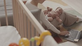 Slowmo of young Caucasian woman with infant daughter lying on her laps working on laptop from cozy home - Powered by Shutterstock - Get 15% off with code: PIKWIZARD15