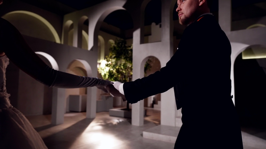elegant couple is dancing waltz in romantic dark ballroom in royal palace