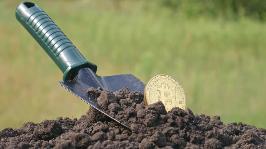 The concept of extraction and mining of cryptocurrency. Bitcoin dug up in the ground | Shutterstock HD Video #1094049745
