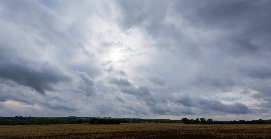 time lapse over the farmer’s pasture. UK. England. Blue sky with moving clouds. Dramatic storm clouds time lapse over rye fields. Storm clouds over field, rain over fields, extreme weather. 
