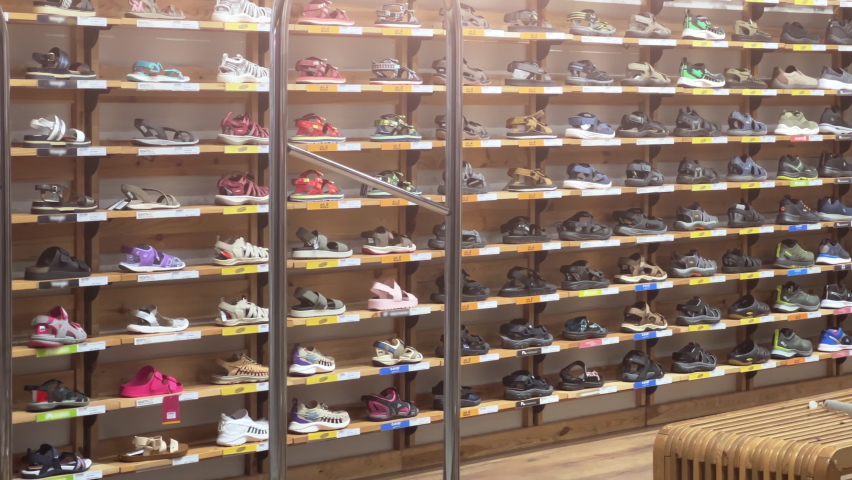 Sports shoes: sneakers and sandals stand on the shelves of a shoe store.