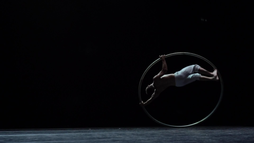 Muscular circus artist perform Cyr Wheel on a black background. Concept of originality, creativity and outstanding Royalty-Free Stock Footage #1094059833