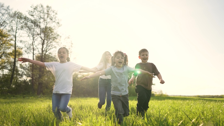 Schoolchildren play in spring vacation park. Active happy group of children run on grass in field in summer. Family outdoors in sun. Child on playground.Happy family concept.School holidays in garden Royalty-Free Stock Footage #1094063611