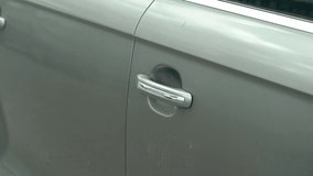 Close-up video of man's hand opens and closes the grey car door. Slow motion