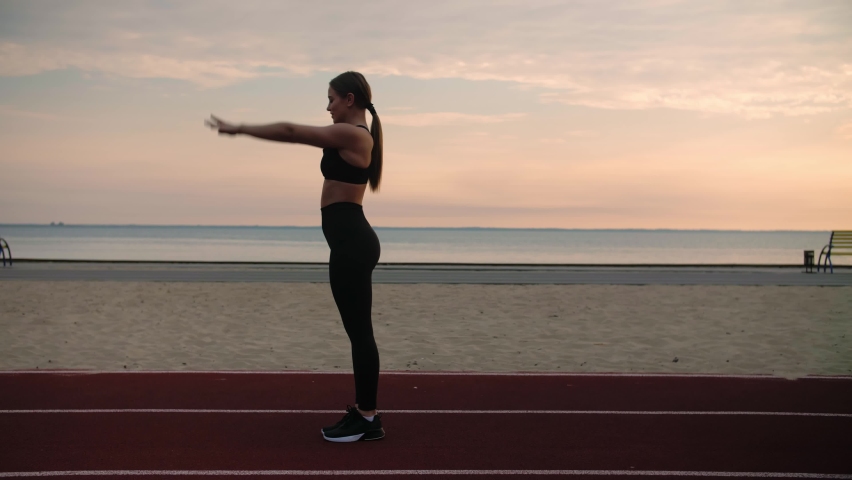 Young woman doing acrobatic activity.Girl training on the beach at sunrise.Doing back flip on playground. High quality 4k footage