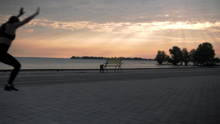 Young woman doing backflips.Girl doing acrobatic activity against the sea at sunrise. Fitness Lifestyle slow motion. High quality 4k footage