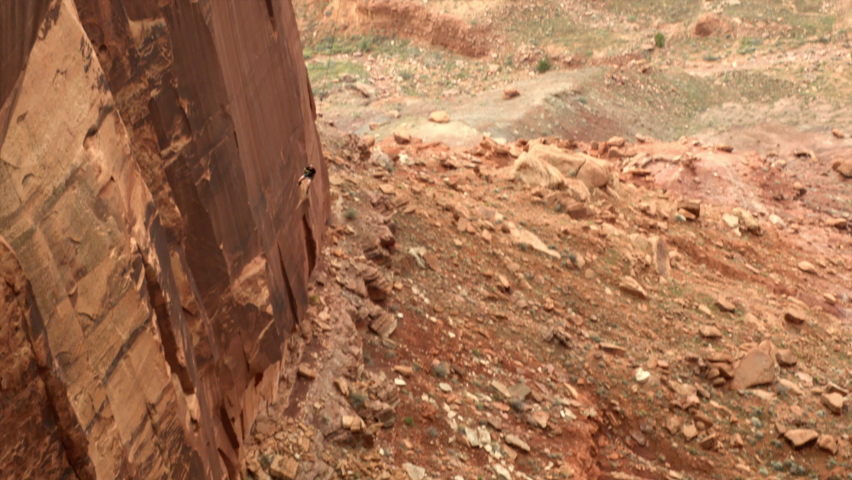 Tracking A Young Man As He Swings Off The Edge Of A Cliff Attached To A Bungee Cord - Moab, Utah
