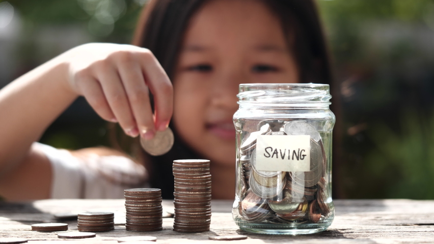 Happy Asian child girl save money by putting coins in glass jar, coin stack growing. Concept of saving money, cash, education, growth, finance, bank, investment, management, income, business Royalty-Free Stock Footage #1094077903