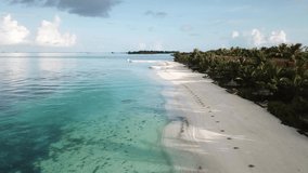 Drone flying above Maldives Island sea shore, blue water, white sand, green palms and villas. 4K