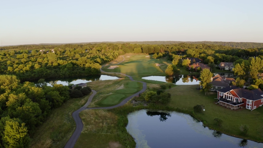 Aerial drone shot over luxurious villas along lake Geneva, Wisconsin, USA surrounded by dense vegetation.
