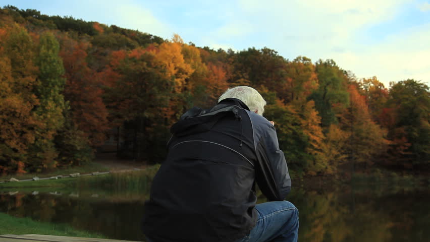 A man relaxing and enjoying the view of the autumn leaves. Camera dollies right