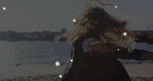 Animation of stars over caucasian woman at beach. Free time and holidays concept digitally generated video.