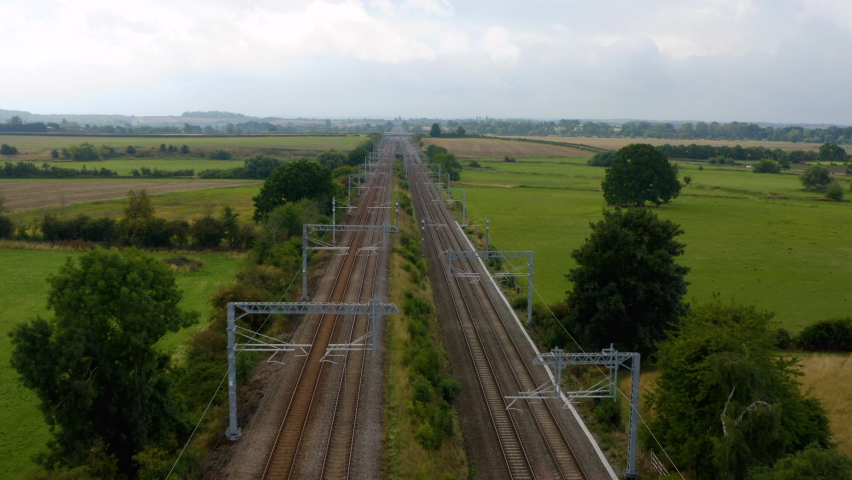 Train track passenger train aerial view of public transport infrastructure. Aerial following view of a high-speed train moving fast on the countryside. 4k aerial horizon view of intercity train.  Royalty-Free Stock Footage #1094086949