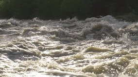 Dirty flood water flowing rapidly in river, closeup abstract detail, slow motion video