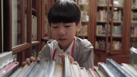 Cute and smart looking Asian elementary student child looking and searching for book from wooden bookshelf in library at school. Self study, reading lifestyle and back to school concept. - Powered by Shutterstock - Get 15% off with code: PIKWIZARD15