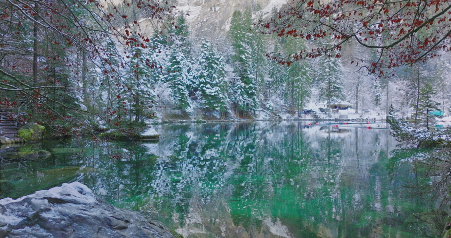 Scenic view of famous mountain lake Blausee located in the Kander valley above Kandergrund in the Jungfrau region, Switzerland. Romantic blue lake nature park in the Bernese Alps during winter season.