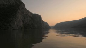 Danube Gorges (Cazanele Dunarii in Romanian language) view from a boat during a beautiful summer sunrise. Cruise on Danube River, 4k video. Landmarks of Romania.